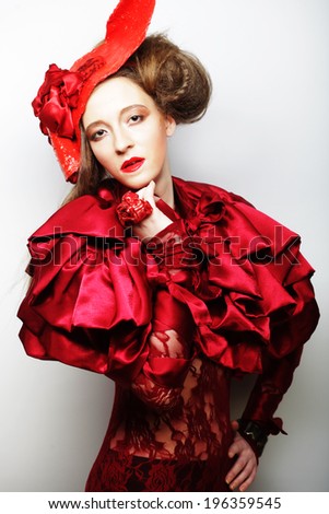 Fashion model in bright red costume and red hat. Studio shot.