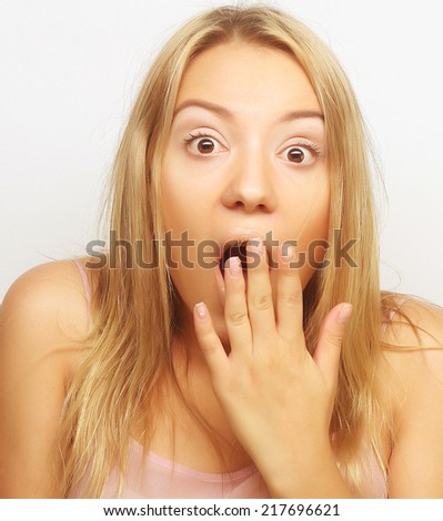 Close-up portrait of surprised blond girl holding her head in amazement and open-mouthed.