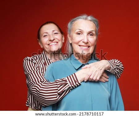 Two elderly women friends hugging on red background. Lifestyle and old people concept. ストックフォト © 