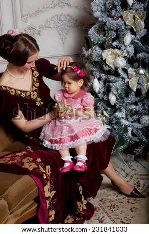 Child with mother receiving near Christmas tree. Retro style.