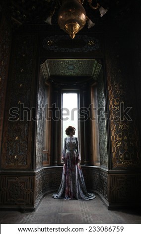 young beautiful woman in pink dress posing in luxury palace