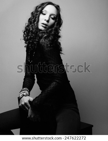 Portrait of beautiful fashion model posing over gray background. Black and white studio shot