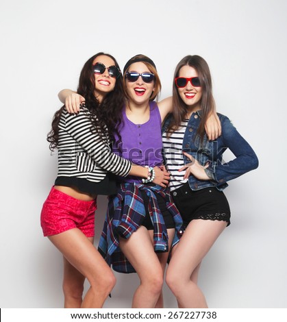 Three stylish sexy hipster girls best friends.Standing together and having fun. Looking at camera. Over gray background.
