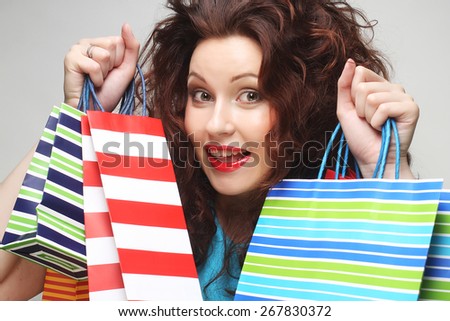 beautiful young woman with colored shopping bags over grey background