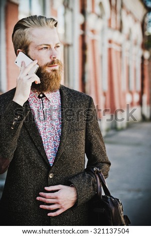 Young bearded man with mobile, outdoor, summer time