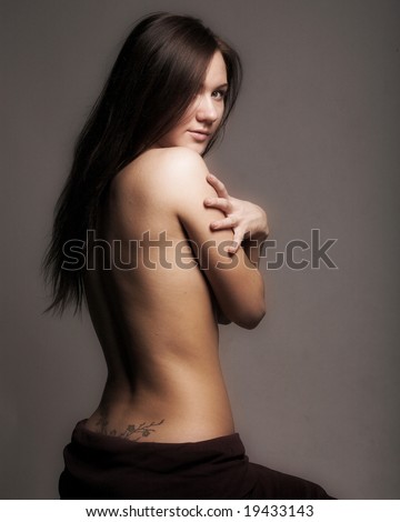 Studio portrait of a topless modest girl in semidarkness