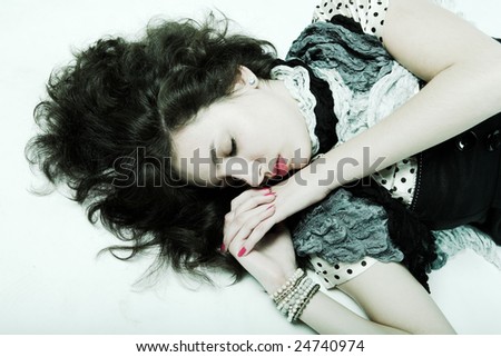 Young woman with long brown  curly hair and green  eyes laying on floor.