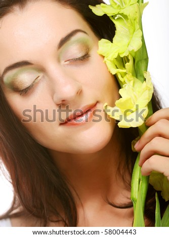 Close-up beautiful fresh face with gladiolus flowers in her hands