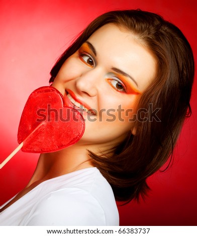 happy woman with heart candy lolly pop. On red background.