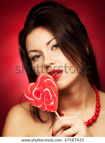 Pretty young woman holding lolly pop.Over red background.