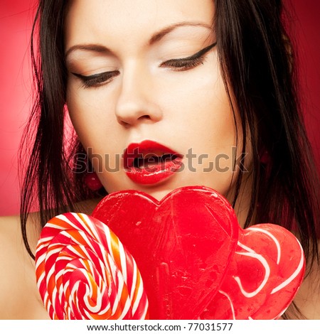 Pretty young woman holding lolly pop.Over red background.