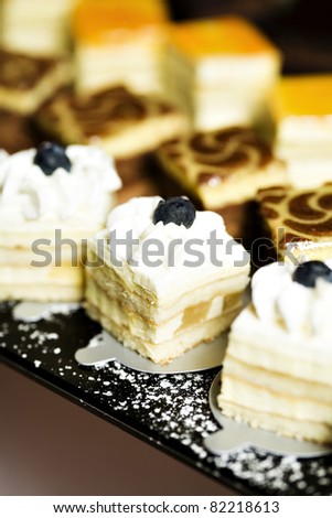 Closeup of a plateau with three types of sweets, miniature cakes. Blueberries with cream, caramel and orange cake. Delicious looking. Designed especially for high class party.