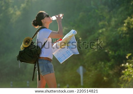 Woman tourist with backpack drinking water in nature