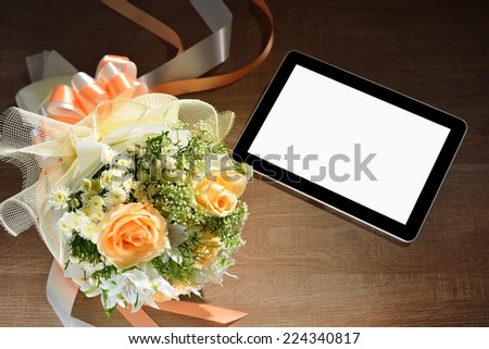 Tablet computer and beautiful bouquet of flowers on wooden background