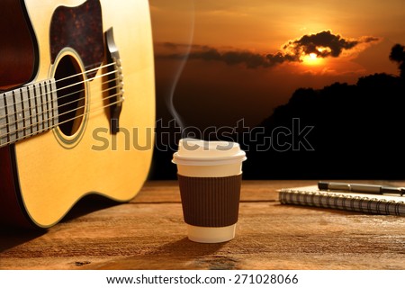Paper cup of coffee and guitar with the sun in background