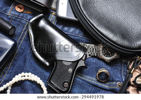 A woman\'s purse and gun and accessories