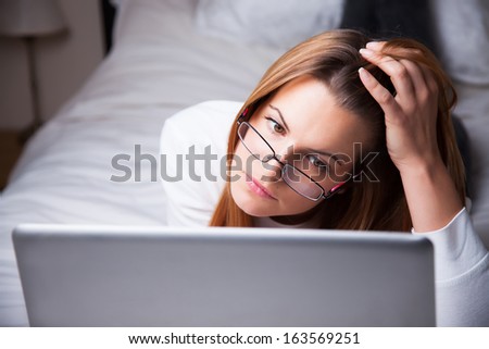 Young woman looking at laptop on her bed