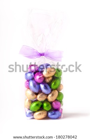 Cellophane bag of colourful chocolate mini easter eggs, with a bow round the top of the bag and a white background