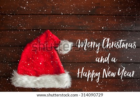Red santa with white fur trim hat on brown wooden floorboards with snow drops effect. Text has a brushed effect.