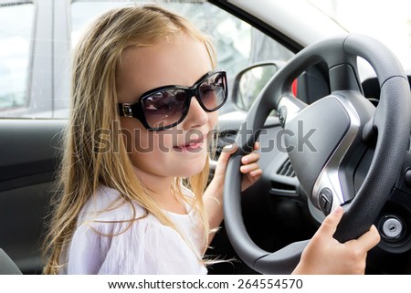 Cute girl driving car in sun glasses