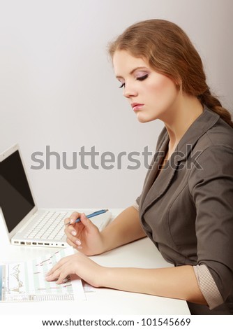 A portrait of a businesswoman sitting at a desk with a laptop, looking back