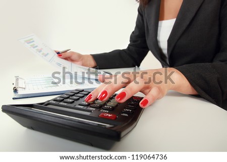 Businesswoman doing some paperwork at her desk using a calculator