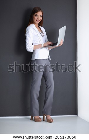 Young woman holding a laptop, isolated on grey background