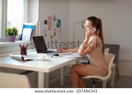 Woman using mobile phone and laptop at home