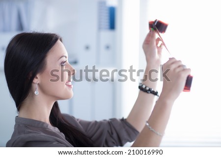 Young woman watching footage on film, standing near window