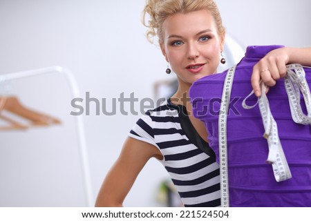 Smiling fashion designer standing near mannequin in office