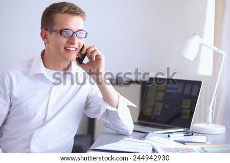 Young businessman working in office, sitting at desk