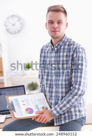 Smiling businessman with red folder sitting in the office
