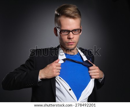 Young businessman acting like a super hero and tearing his shirt, isolated on gray background