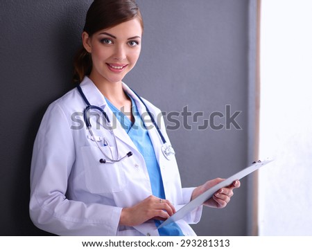 Young doctor or medic with clipboard and stethoscope isolated on grey background