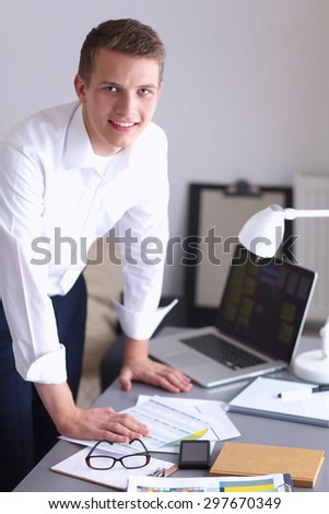 Young businessman working in office, standing near desk