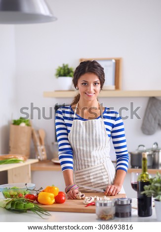 Young woman cutting vegetables in kitchen, standing near desk