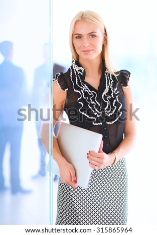 Portrait of a beautiful office worker standing in an office with colleagues in the background