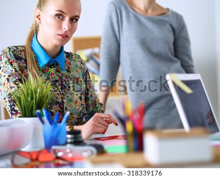 Portrait of a beautiful office worker sitting in an office with a colleague behind her