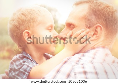 Heartwarming hugs little son and his father in warm sun shins