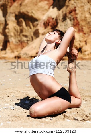 Yoga practice. Close up image of young girl doing king pigeon yoga pose on the beach