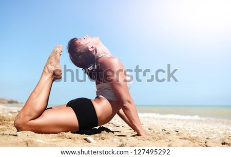 Young woman doing full cobra yoga pose at the deserted sea coast