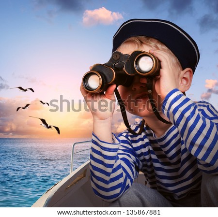 Sailor boy looks at horizon from binoculars