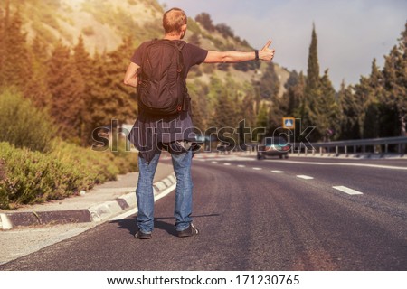 Hitchhiking traveler try to stop car on the mountain road