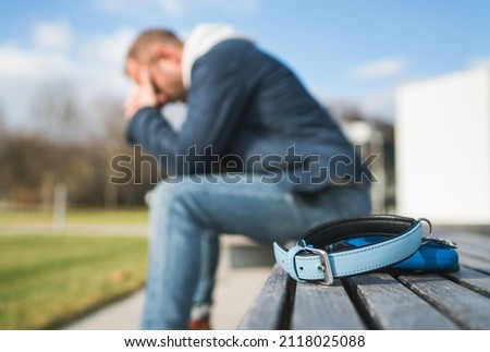 Broken with grief man dog owner is grieving sitting on a bench with the lovely pet collar and deep weeping about animal loss. Home pets relatives and love concept. Foto stock © 