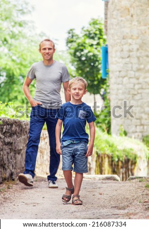 Little son walk oh old street town with his father