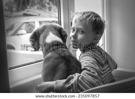 Little boy with his dog waiting together near the window