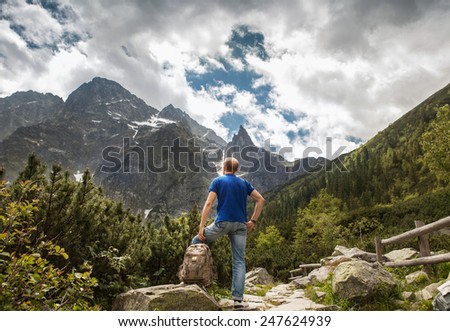 Mountain traveler looks on wild rocks