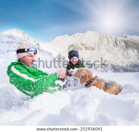 Cute family scene: father and son play with dog during mountain walk