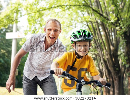 Father learn his son to ride bicycle
