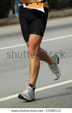 Two active male legs of a matured sportive caucasian white male jogger athlete running in a marathon competition on the road outdoors